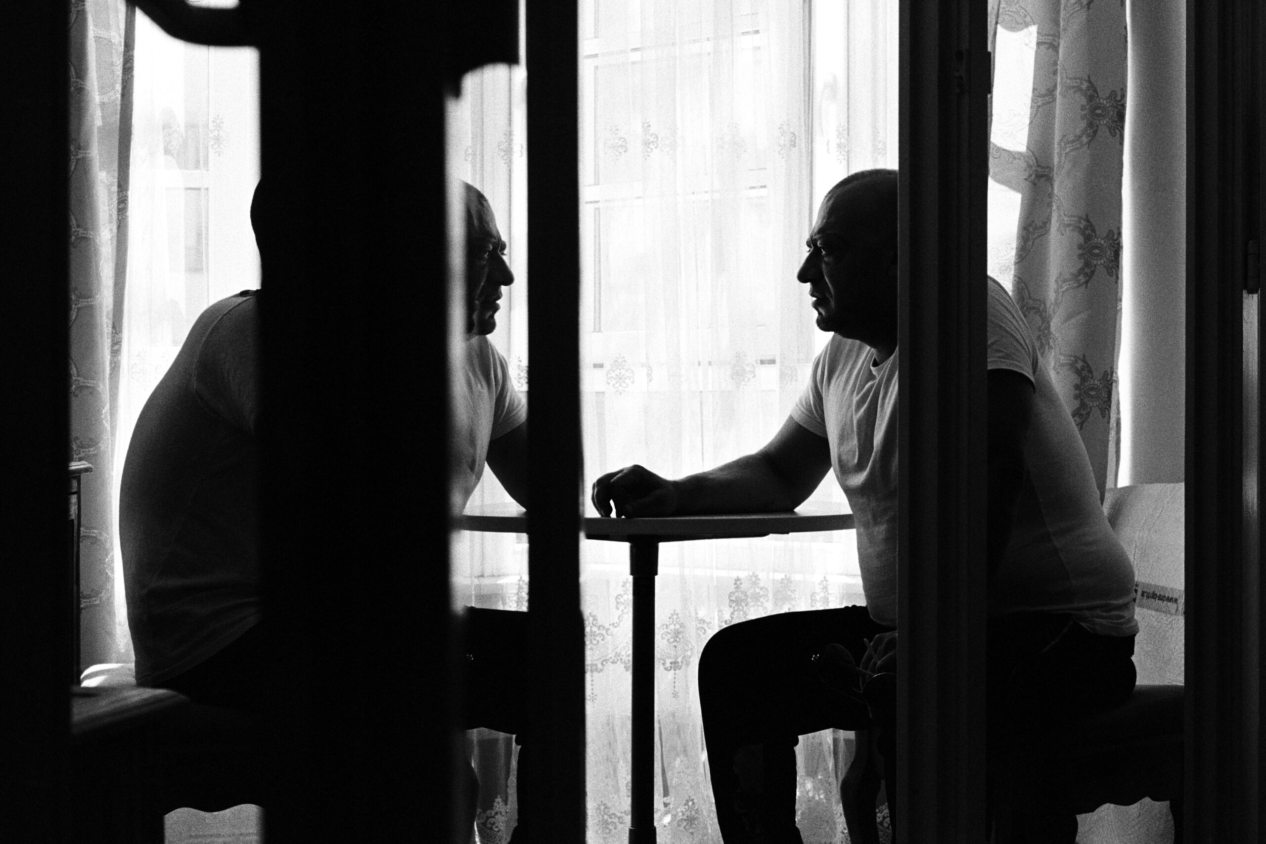 Two men sit across each other at a table.