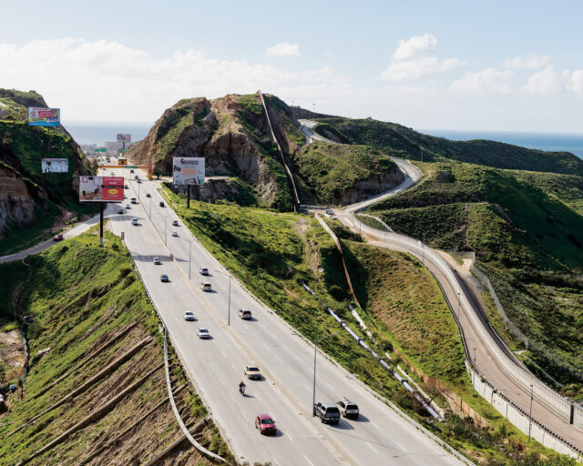 An aerial photograph of a freeway bisecting lush green hills.
